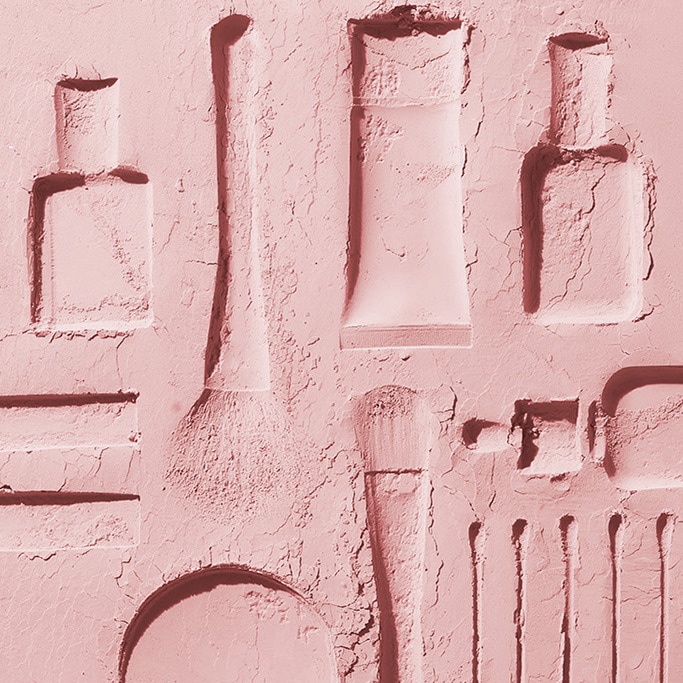 Pink sand imprints of iconic beauty products. 